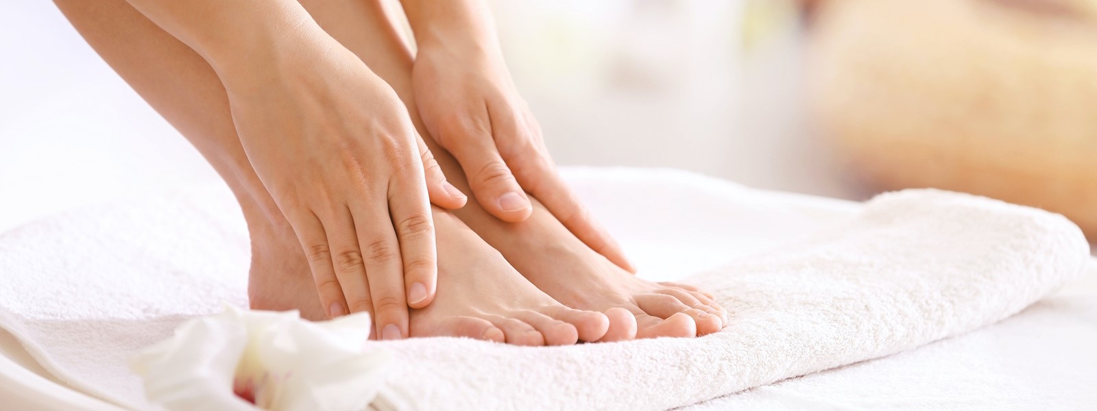 Hands massaging their own bare feet on a white towel